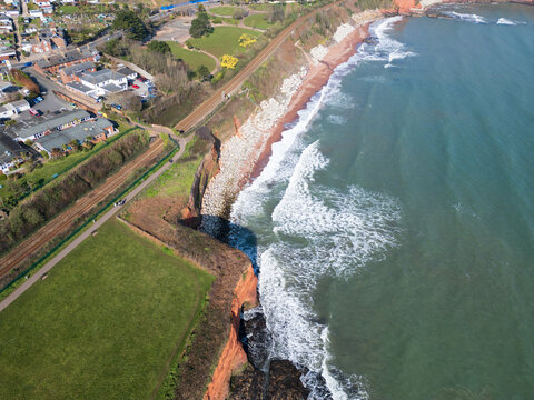 Aerial view of Hollicombe Beach with its distinctive red sandstone cliffs, a coastal railway line, and waves breaking on the shore Torquay, Devon, United Kingdom.