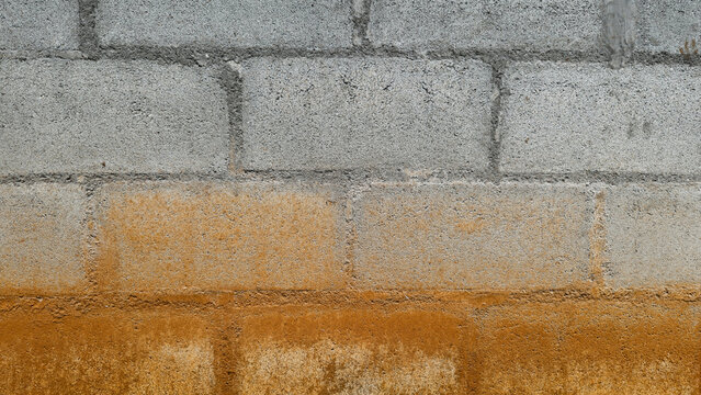 Grunge concrete block wall texture background with orange rust stain. Weathered cement brick surface with dirty industrial gradient pattern for background.