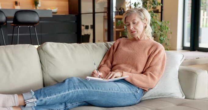 Woman, writing and planning with notebook in lounge, thinking and goal setting with memory on couch. Personal growth, reflection and mature person with diary, notes and future manifestation in house