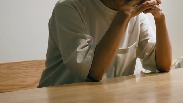 Person in White Shirt Looking at Smartphone on Wooden Desk