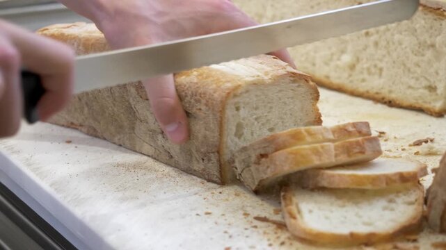 Fresh bread is sliced by kitchen staff for bruschetta preparation during catering work for a large party and restaurant event.