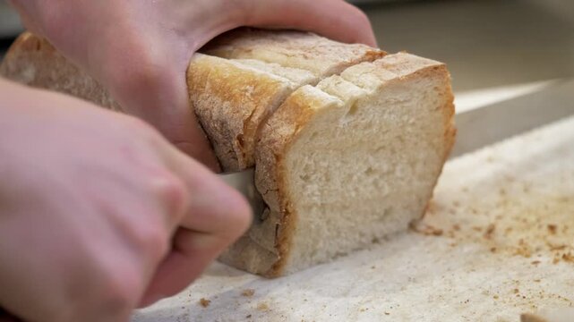 Cook cuts fresh bread into even slices for bruschetta while preparing appetizers for a festive gathering in a professional kitchen