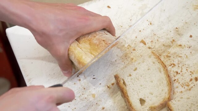 Close up of fresh bread being sliced for appetizers during food preparation in a busy restaurant kitchen before an event.