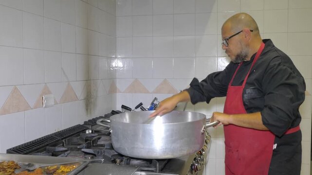 An expert chef skillfully tosses pasta sauce in a pan with confident technique, demonstrating years of culinary mastery while preparing a flavorful dish for a busy restaurant celebration event.