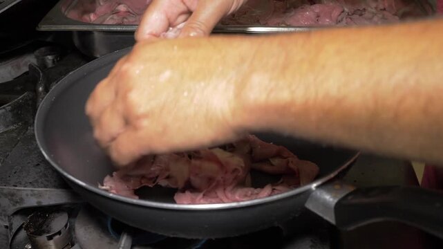 A chef cooks beef straccetti over a high flame in a sizzling pan, the intense heat quickly searing the meat strips for a flavorful dish at the restaurant party event.