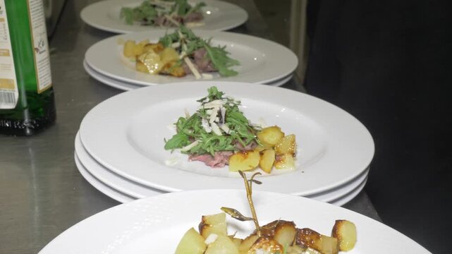Steam and rich aroma rise from beef straccetti as they cook in a sizzling pan, filling the restaurant kitchen with the inviting scent of this hearty dish for the party.