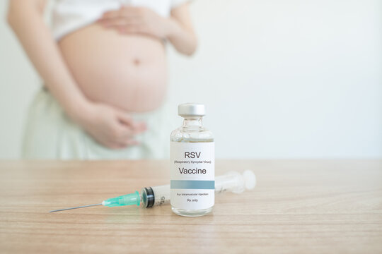 RSV vaccine bottle and syringe on clinic table with blur pregnant woman background. Respiratory Syncytial Virus vaccine protect pregnancy woman and infants from respiratory tract diseases.