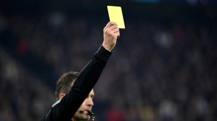 Soccer Referee Holding Up Yellow Card in Crowded Stadium