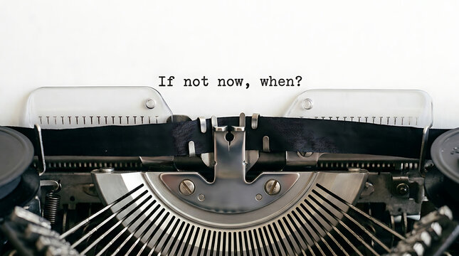 Vintage mechanical typewriter typing an inspirational quote If not now, when? on paper
