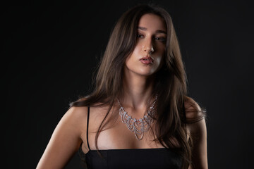 Fototapeta premium Female model wearing a beautiful sparkling diamond necklace and black dress in studio
