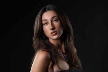 Naklejka premium Young woman posing for a fashion and beauty portrait against a dark background