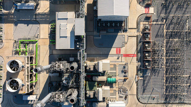 Aerial view combined cycle power plant with cooling tower and substation under blue sky, Industrial infrastructure of electric power station, exhaust stack and cooling systems.