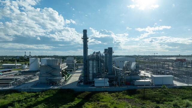 Aerial view combined cycle power plant with cooling tower and substation under blue sky, Industrial infrastructure of electric power station, exhaust stack and cooling systems.