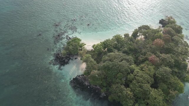 Aerial Of Rocky Forested Islet With Volcanic Rocks And White Sand