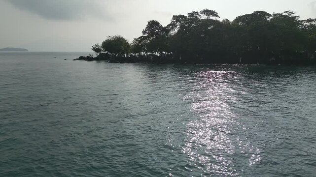 Aerial Along Rocky Mangrove Islet With Sun Glitter On Calm Sea