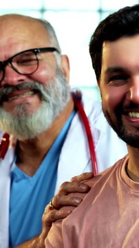 Indian male doctor with young male patient smiling showing ok sign after successful treatment as experienced physician gives thumbs up inside modern Indian clinic OPD healthcare visit