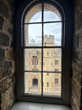 View from inside a stone room looking out a window towards a historic castle tower