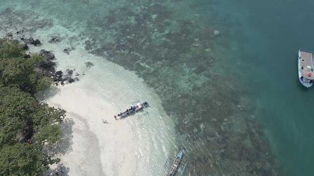 Top Down Aerial Of White Sand Spit Black Rocks And Boats Lampung