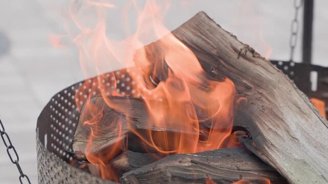 blazing firewood in fire pit close up for outdoor fire background with intense flames and logs