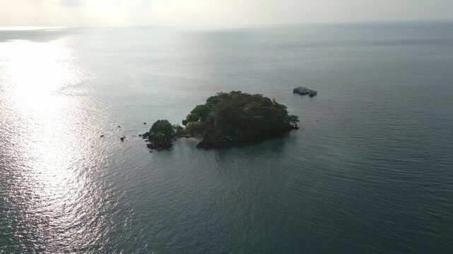 Aerial Sunrise Pullback Over Forested Islet Calm Sea Sebesi