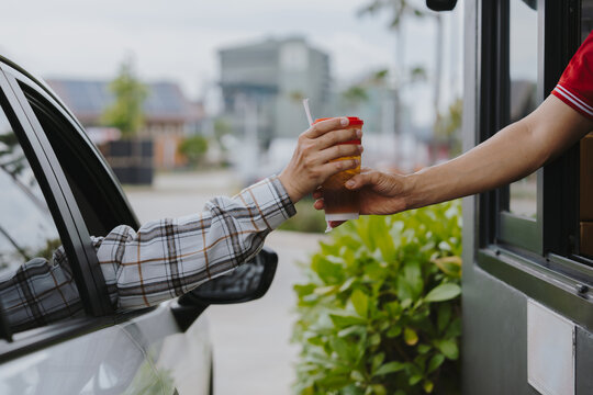 People pick up food and drink glasses from drive-thru counters and take them to eat at home and at work.	