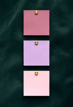 Three Pastel Sticky Notes Pinned to a Dark Textured Surface
