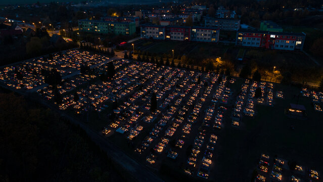 Aerial view of a cemetery at night with thousands of glowing candles on graves near residential buildings in Debrzno, Pomeranian Voivodeship, Poland.