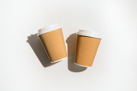 Two takeaway coffee cups on white background with shadows, flat lay and copy space