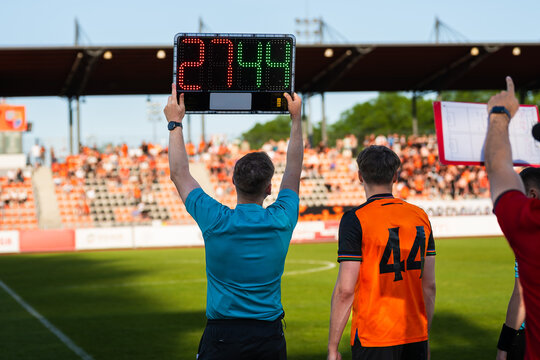 Assistant referee displaying substitution board during a soccer match with stadium crowd in the background