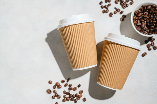 Takeaway Coffee Cups with Roasted Coffee Beans on Light Background, flat lay