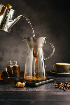 Pour hot water over coffee brewing with dripper and kettle, specialty coffee preparation, dark background, still life