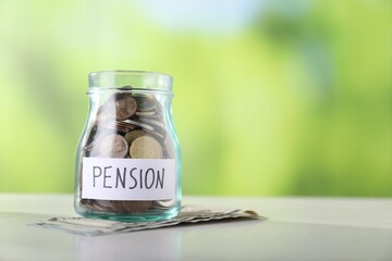 Obraz premium Jar with word Pension and money on light table against green background, closeup. Space for text