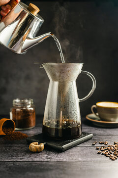 Pour hot water over coffee brewing with dripper and kettle, specialty coffee preparation, dark background, still life