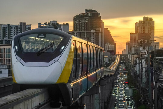 Bangkok's MRT train system, serving the city center, offers a backdrop of a stunning sunset with golden sunlight.