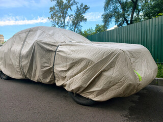 Automobile shielded with nylon car cover in residential parking lot protecting paint and exterior © Harmony Video Pro