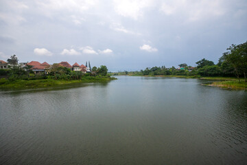 Fototapeta premium A beautiful and peaceful view of a serene lake and lakeside residential area in Kota Baru Parahyangan, West Bandung, Indonesia. A tranquil suburban neighborhood.