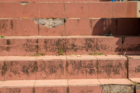 Red-tiled steps. The steps show significant signs of wear and tear, including broken tiles and exposed concrete.