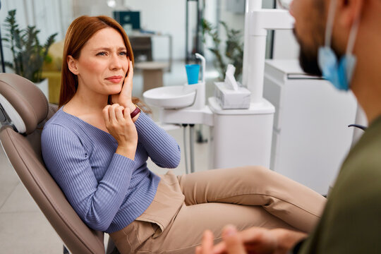 Woman experiencing toothache consulting dentist in clinic