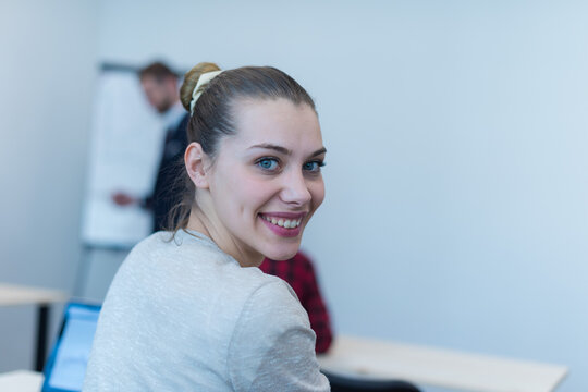 Confident Young Businesswoman Looking Back and Smiling in Classroom Setting