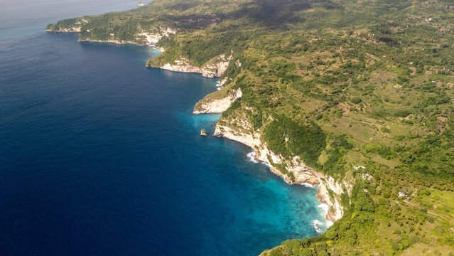 Green rocky cliff over turquoise ocean aerial photo Nusa Penida Bali Indonesia drone