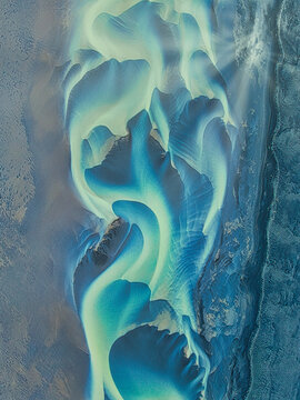 Aerial view of the intricate braided glacial river patterns of Solheimasandur with turquoise water flowing over dark volcanic sand in Vik, Myrdalshreppur, Iceland.