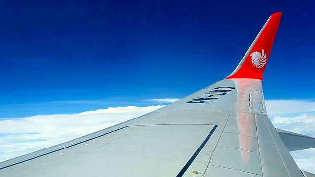 Ternate, 26 June 2026: "Airplane wing with red winglet flying above white clouds"