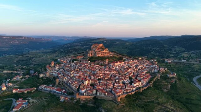 Aerial view of Morella, medieval walled town with complete perimeter walls and hilltop castle at sunrise, Els Ports valley landscape, Castellon, Valencian Community, Spain