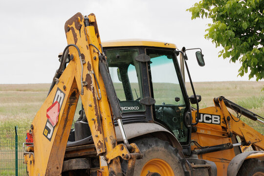 Yellow jcb backhoe loader parked in field