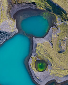 Aerial view of vibrant turquoise and emerald green volcanic crater lakes surrounded by black sand and mossy slopes near Myrdalsjokull, Vik, Myrdalshreppur, Iceland.