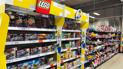 Naklejka premium Hohenlimburg, Germany - June 12, 2026: Brightly lit toy aisle with LEGO sets displayed on shelves inside Kaufland supermarket