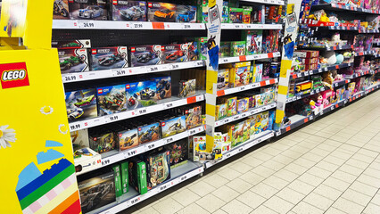 Naklejka premium Hohenlimburg, Germany - June 12, 2026: Supermarket aisle stocked with LEGO toy sets and other toys displayed on shelves inside Kaufland supermarket