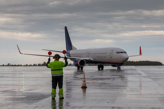 Airplane marshalling at the aiport in rainy weather. Passenger airliner meeting