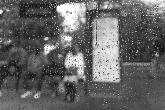 Rain Drops on Window with Blurred Urban Pedestrians in Black and White
