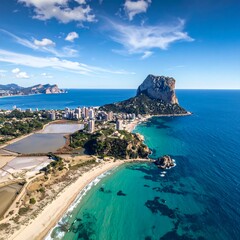 Obraz premium Aerial view of a coastal town with a sandy beach, clear turquoise water, and a prominent rock formation
